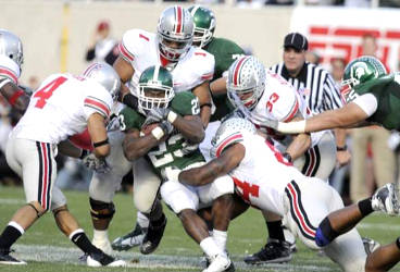 Michigan State's Javon Ringer is hit hard by a host of Ohio State defenders Saturday. Ringer was held to 69 yards rushing. (Photo: Rod Sanford, Lansing State Journal)